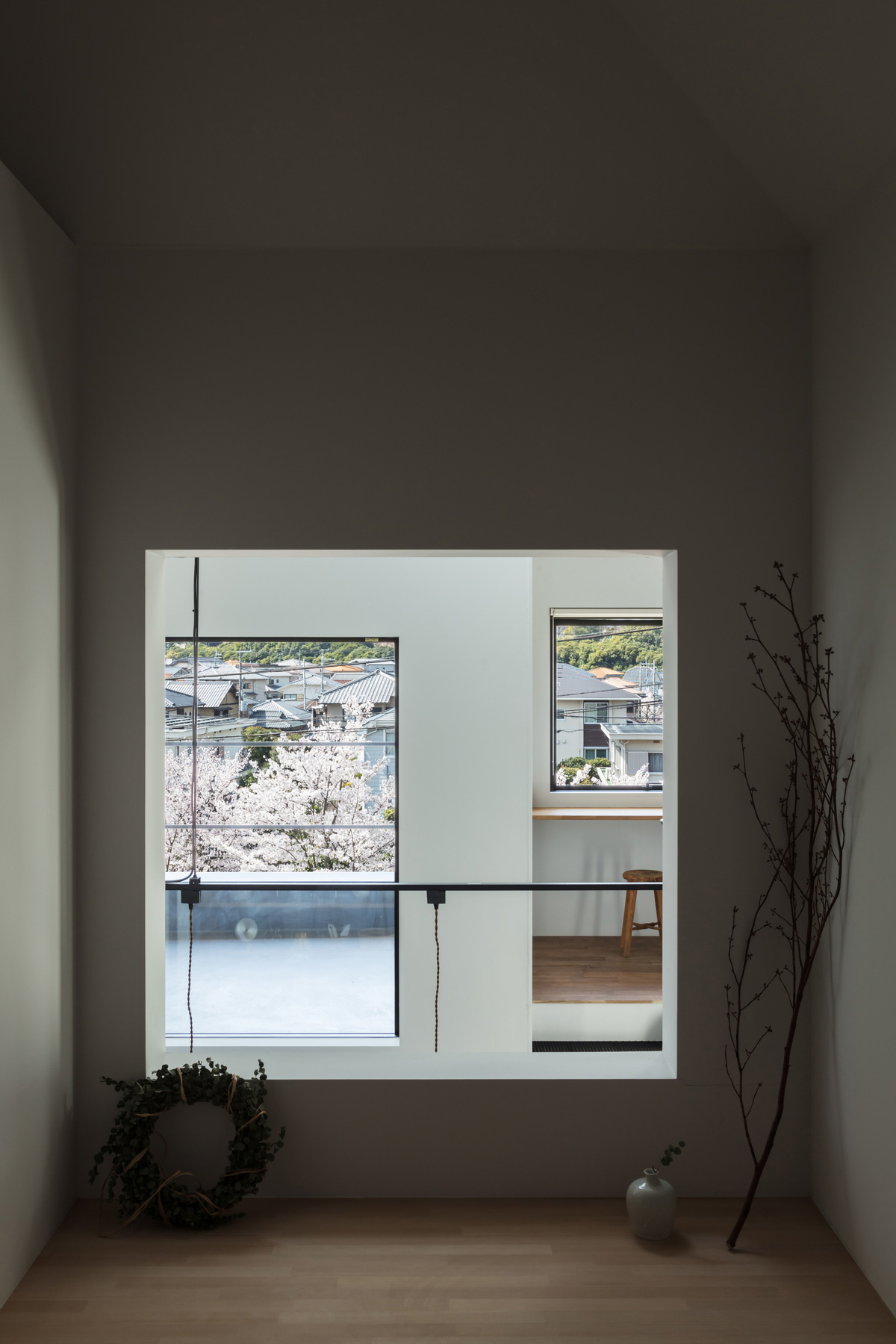 和室の窓から大きな家、テラス、桜並木を見通す。