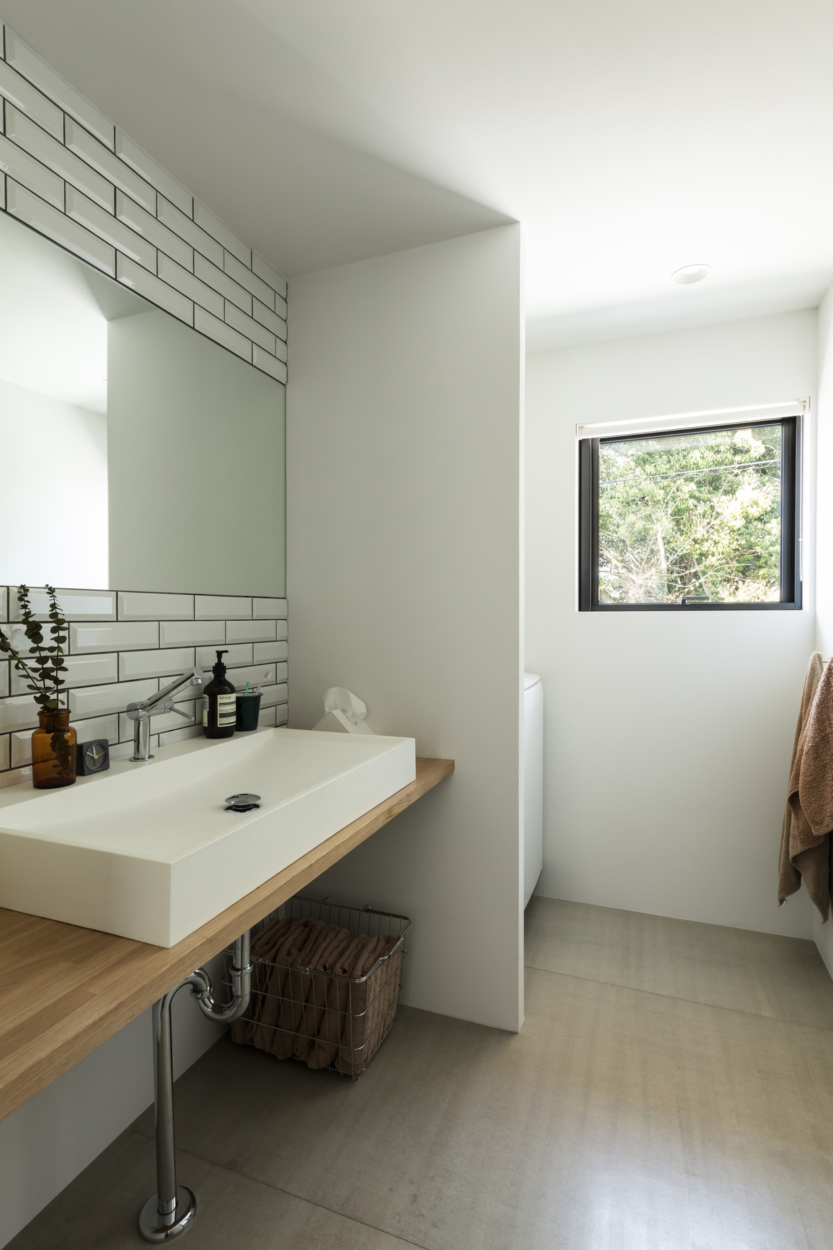 雑木林の緑を楽しめる洗面室・浴室。壁面はサブウェイタイル。