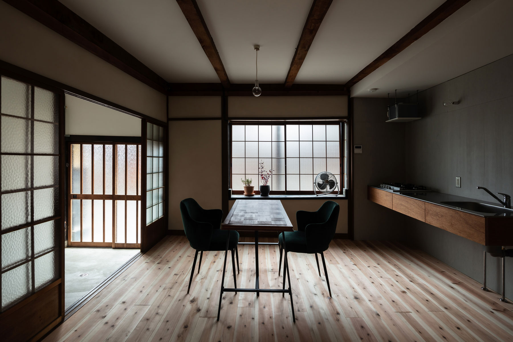 シンプルな壁付けキッチンと家電置き場として設えた出窓でテーブルをL形に囲むダイニング。