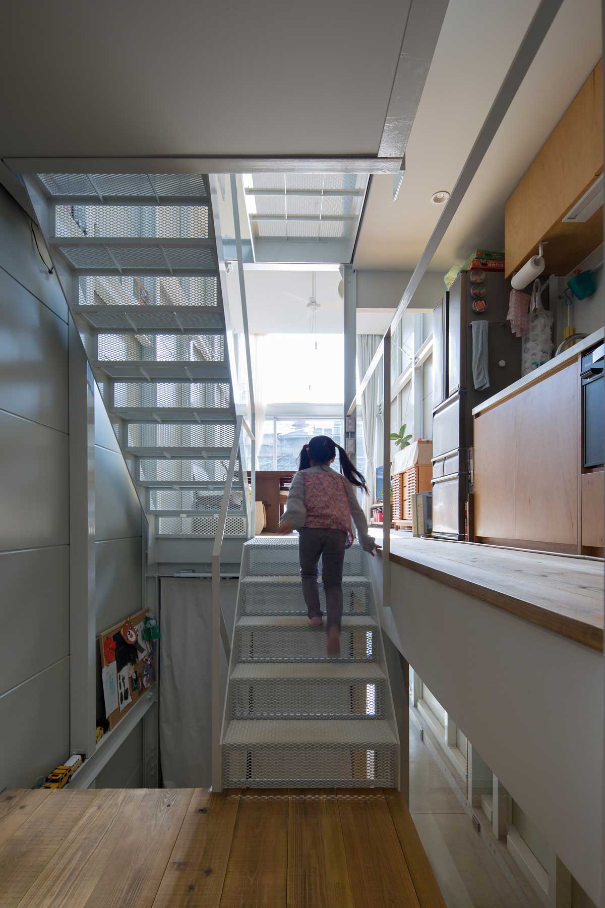子供部屋からLDKとキッチン方向を見る。階段が上下に散らばる住まいの断片を１つにつなぐ。