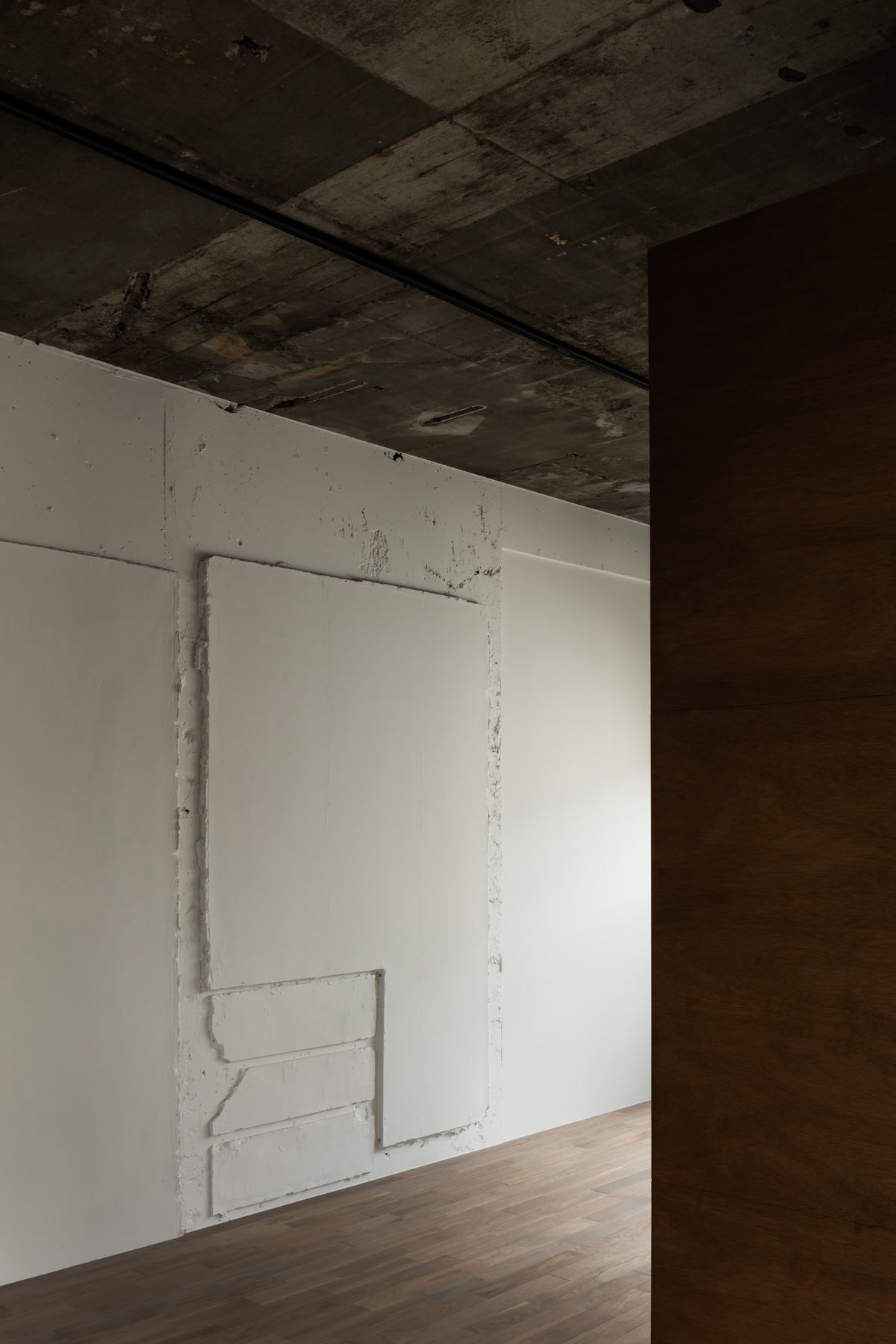 壁面に刻まれた履歴が白く抽象化され、解釈の余地が生まれる。