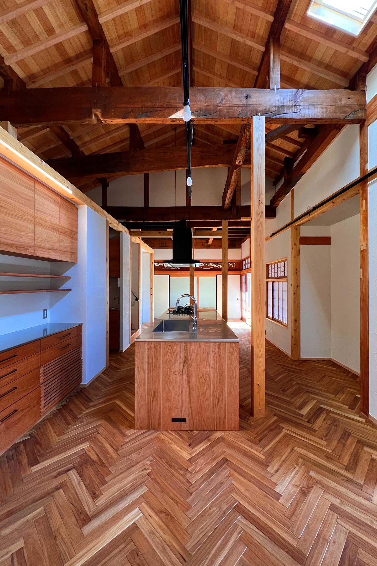 東西に長い既存建物の特性に合わせて、居間はダイニング・キッチン・リビングの順に繋げたDKL。リビングはさらに8帖の和室へ続く。右手の書院障子は2階から移設したもの。