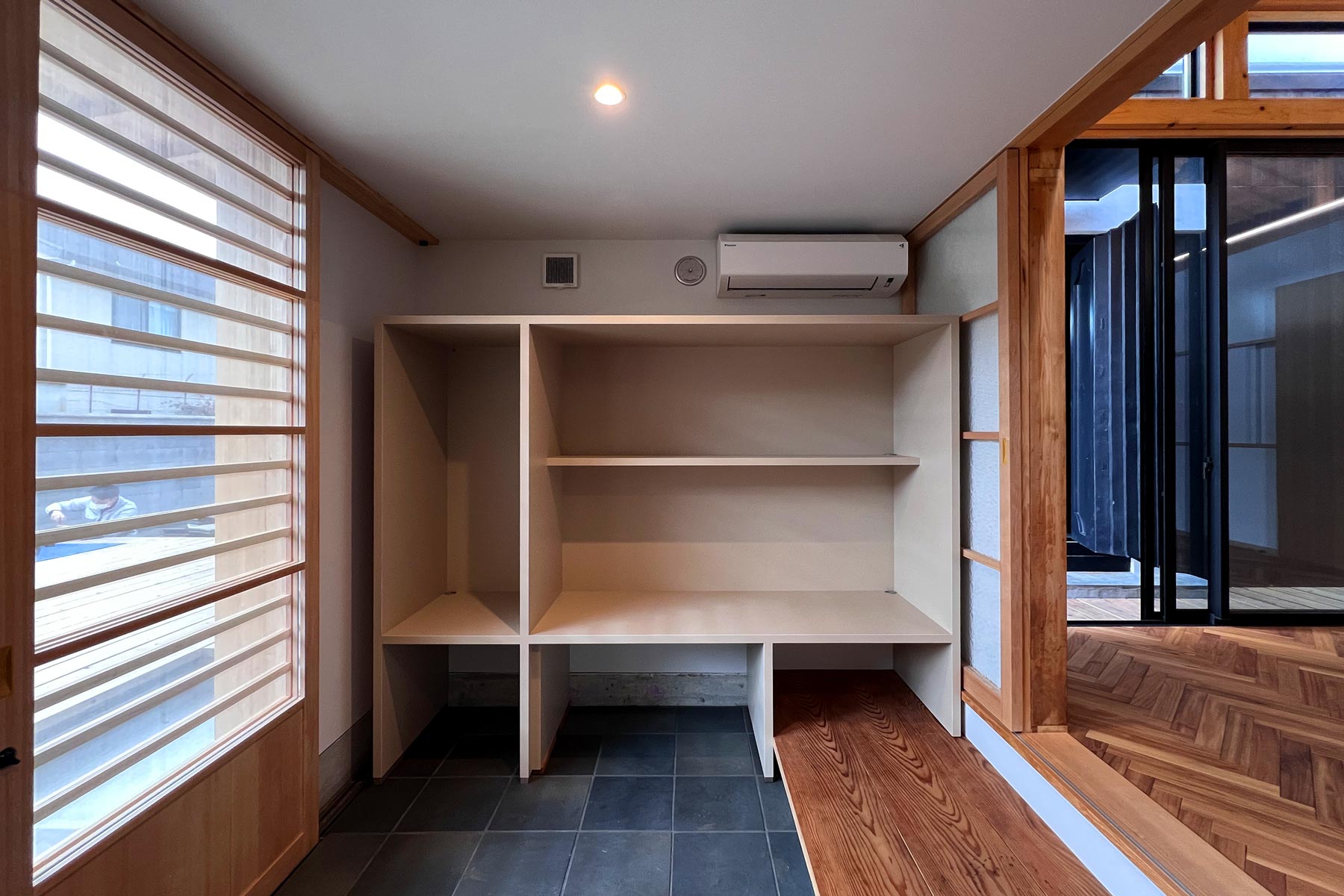 ペット室を兼ねた多目的室な土間。床は色むらのある敷瓦。式台は既存玄関からの転用。モモンガ・イモリ・うなぎ、その他小動物たちのための造り付け棚。