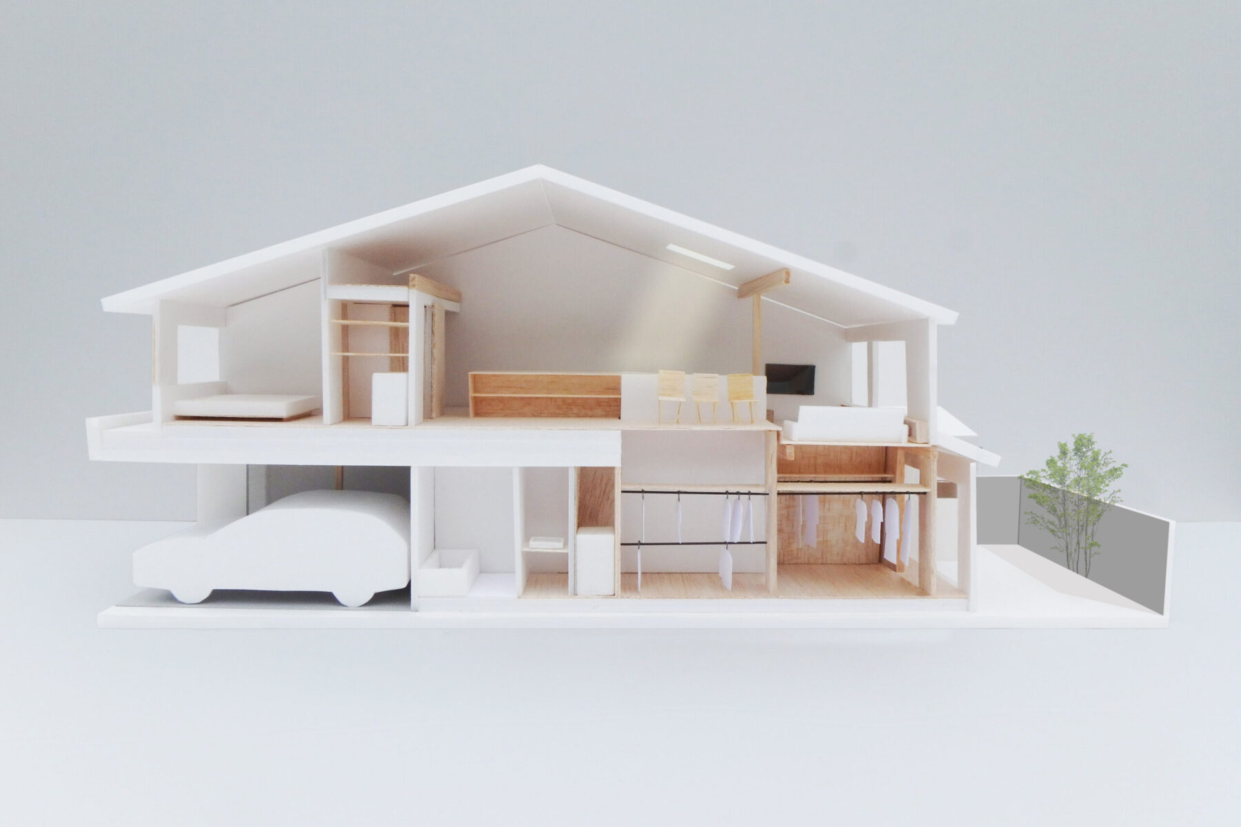 大家族のための京町家改修。駐車場と駐輪場、沢山の子供部屋と収納を限られた容積の中で確保しながら、家族全員が若干の距離を保ちつつ生活できるように、既存の柱梁を足掛かりにして様々な高さに水平面を差し込み、三角屋根の家形断面の中に多様な居場所を生み出しています。